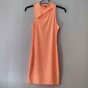 Klänning - Tajt neon orange/aprikos- klänning. Snitt över brösten. Nyskick