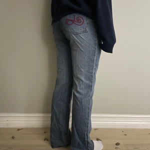 Jeans - Snygga urtvättade blå jeans med detalj på fickan. Dom är egentligen i stl 40 och ska sitta tight och mer bootcut. Jag har vikt ner dom så dom är egentligen högmidjade. Hör av dig om pris eller funderingar!