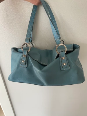 Tommy Hilfiger väska - Säljer min ljusblå väska från Tommy Hilfiger som är i fint skick.   Mått Längd: 30 cm Bredd: 15cm