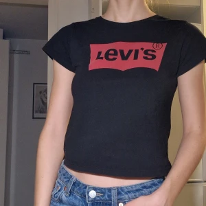 Levi's T-shirt - Levi's T-shirt. Något croppad (slutar precis vid naveln). Litet hål starx under armhålan, bör vara lätt att laga.