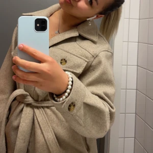 Beige kappa  - Säljer denna superfina beiga kappan ❤️Sitter jättefint och har ett band att knyta över midjan med men är lika fin utan 