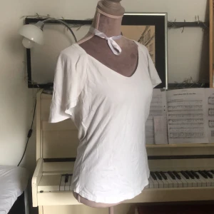 Vit topp - En gullig vit topp med medelhög v-neck och fina lite fleared ärmar. Materialet är rätt genomsynligt och har ett litet hål framme på bysten (se sista bilden). 