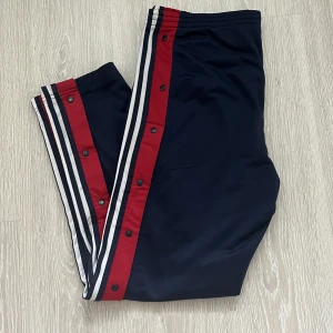 Adidas byxor - Track pants från adidas i använt men bra skick. Knapparna på byxbenen är alla hela och går och öppna och stänga. Köpte på humana ☺️