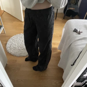 Adidas trackpants - Ett par superfina adidas trackpants, dem är svarta med gråa ish ränder. Sitter lågmidjat och passar någon som är 160 - 170 beroende på hur man vill att dem ska sitta!💗 skriv för intresse eller andra frågor!! Kan tänka mig att sänka priset!