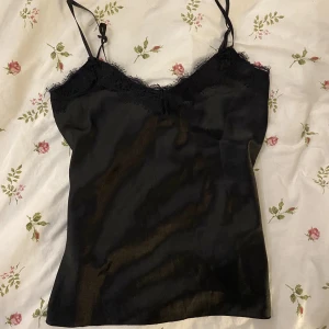 Svart spets linne - Det är ett svart spets linne som kan användas både som pyjamaslinne men även ett vanligt plagg. Materialet är silkes tror jag då det känns som det. Skriv vid fler frågor 💕