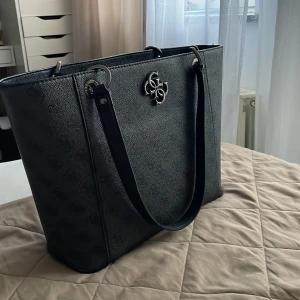 Guess Väska  - Vill sälja min Guess väska som ser nästan ny ut. Den är köpt förra året men knappt använd. Ny pris på den är 1499kr och vill sälja den för 600. Pris kan diskuteras på