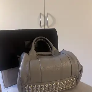 Cool väska i fint användt skick, köpt på Vestiaire för runt 3000kr. Alexander wang rockie bag i en ljusgrå lite beige färg med silver detaljer. Säljer även en likadan i svart!