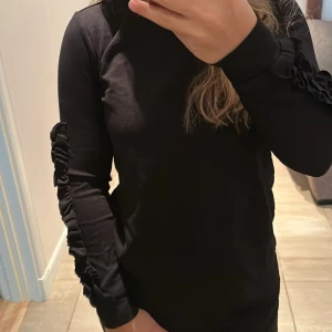 Sweatshirt  - Svart sweatshirt med volang detaljer på armarna. En snygg tröja som passar perfekt till hösten. Tröjan är i bra skick och säljer pga den inte kommer till användning. 