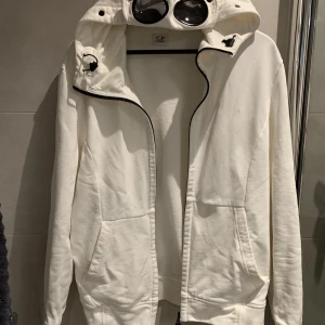 C.P. Company Zip Up Hoodie W/ Goggles - Riktigt soft Cp company hoodie  Cond 8/10, Inga hål dock liten fläck längst ner på ryggen som knappt syns. Strl L men sitter mer som M Nypris 2500kr Mitt pris: 1199kr!🤝🏼 Hör av er om ni har några frågor eller vill se fler bilder!!🌟