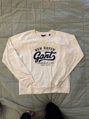Gant sweatshirt - Jättefin krämvit GANT sweatshirt med väldigt snyggt marinblått tryck, tecken på användning men bra skick ändå, köpt o en GANT affär i Stockholm för ungefär 700kr