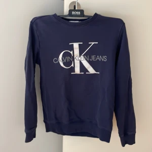 Calvin Klein Jeans collegetröja - En Calvin Klein collegetröja, skick 9/10. Den heter storlek 14, men gissar att den motsvarar ungefär 154.