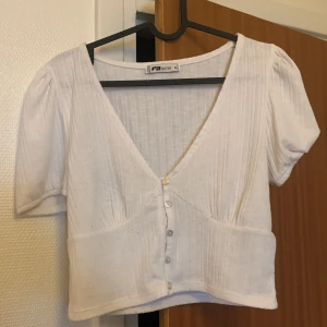 Vit topp  - En vit topp med knappar vid bröstet, perfekt nu till sommaren!