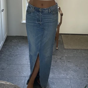 Lång jeanskjol - Lång snygg jeanskjol i storlek W31 L32 med slits både fram o bak. Omsydd till kjol av ett par jeans från Jack and Jones. Jag är 173cm lång. 