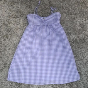 Söt klänning  - Lila och vit-rutig klänning från h&m divided. Storlek 32. Bra skick, använt 1-2 gången. Kan tänka mig att sänka priset. 30 kr + frakt.