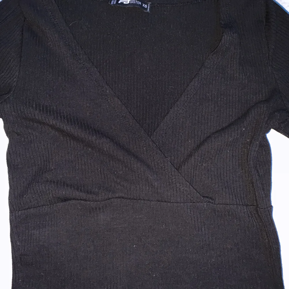 En svart långärmad tröja med korsat tyg högst upp, använt denna några fåtal gånger. . Toppar.