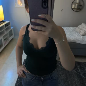 Mörk grönt linne med spets - Ordinarie pris är ungefär 60/70 kr, har använt linnet 3/4 gånger. Jag säljer den för att ja inte tycker om den på mig, så det är inget fel på den. Jag har xs på den, den är stretchig och det går att justera banden. Från new yorker