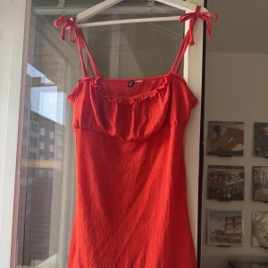 Röd sommarklänning  - Superfin sommarklänning från hm. Kort i modellen och relativt åtsittande men inte bodycon. Har rosetter på axlarna som inte är justerbara   Helt oanvänd!  