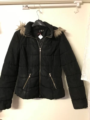 Snygg jacka med huva - Svart snygg vinterjacka från H&M med avtagbar huva med pälskant. Storlek 34.