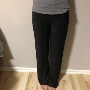 Glitterbyxor - Svarta glittriga byxor, går att ha som low rise eller high waist. Dom är loose på S men är stretchy så dom passar M-L också med då är dom mer thighta. Tunt material och ganska långa ner över ankeln.