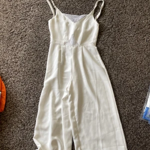 Vit jumpsuit  - Vit jumpsuit, saknar märke och storlek. Väldigt fin. Lite lite lite genomskinlig i material där bak. Spets fram och baktill. Skönt material. 