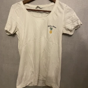Vit T-shirt  - Vit enkel t-shirt med litet ananas tryck på. Köpt från polen för några sommrar sen. Är i mycket fint skick