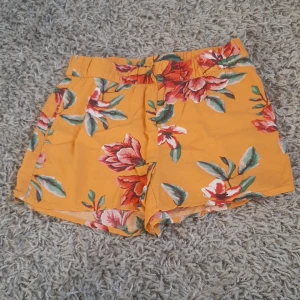 Sommar shorts - Ett par blommiga orangea barn shorts. Original pris är 249kr.