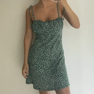 Blommig klänning från H&M - Grön/vit supersöt blommig klänning från h&m säljes med fina  knytningar💚