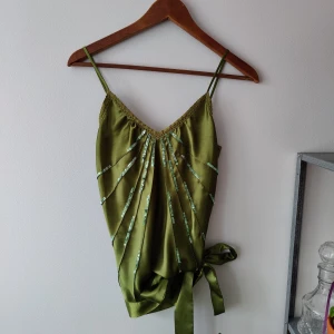 Grön topp  - Jättefin topp i silke med paljetter och band man knyter längst ner. Skön till sommaren. Stl. S 