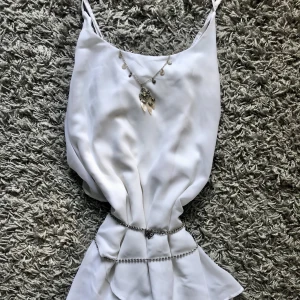 Vit Klänning  - Vit klänning från Vero Moda i storlek L. Axelbanden går i kors på ryggen. Använd högst 3 ggr sen köpt. Katt finns i hemmet. (Smycken ingår inte.)