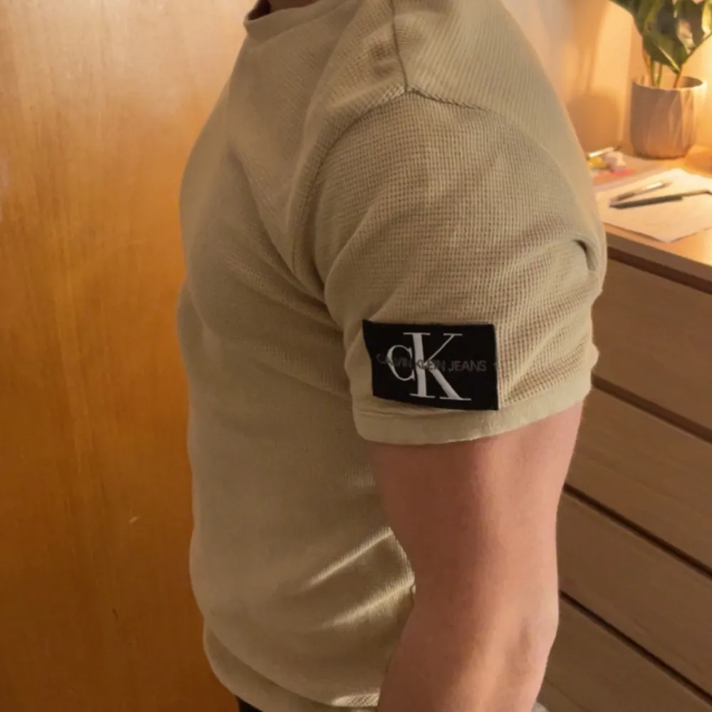 Beige stickad t-shirt från Calvin Klein. I bra skick.  Storlek M men sitter lite tight. . T-shirts.