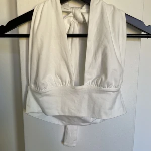 Vit topp - Aldrig använd. Knytning bakom nacken. Lite stor i storleken.