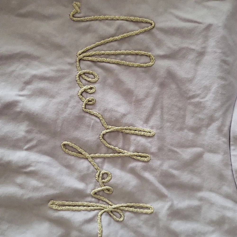 11-12Y lila ärmlös tröja med axelvadd in byggt i tröjan. Är i bra skick, aldrig använd. Det står New York i mitten av tröjan med guldig text i skrivstil. Gjord av ekologisk bomull. . T-shirts.