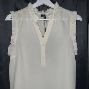 Vit blus - Krämvit blus med volanger från vero Moda i storlek xs.  Prislappar kvar  Nypris 279kr.