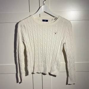 Stickad tröja GANT - Vit stickad tröja från GANT. Perfekt att ha över en klänning eller till en kjol eller snygga byxor. Strl: 146-152