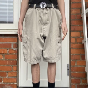 Feta baggy shorts! - Snygga baggy shorts i beige färg. Perfekt skick. Sitter perfekt med ett bälte. Modellen är 182cm. Möts i Malmö och tar Swish. Står ej för frakt eller postens slarv! :)