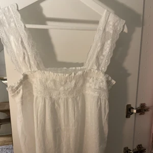 Vit topp med brodyr - Söt vit prickig topp med brodyrdetaljer över bröstet och axelbanden.