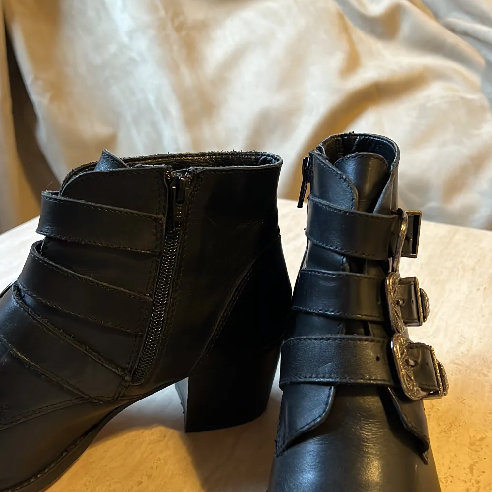 Ankelboots i svart skinn inköpta på Nilson. Dragkedja på insidan med 3 spännen som går över. Använda ca 10 ggr och behöver inte sulas om än på länge. . Skor.