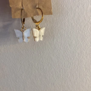 Örhängen  - Ett par örhängen med fjärilar. Fjärilarna sitter i en ring.