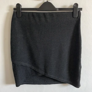 Ribbstickad minikjol - En minikjol i ribbstickat material. Mörkgrå.