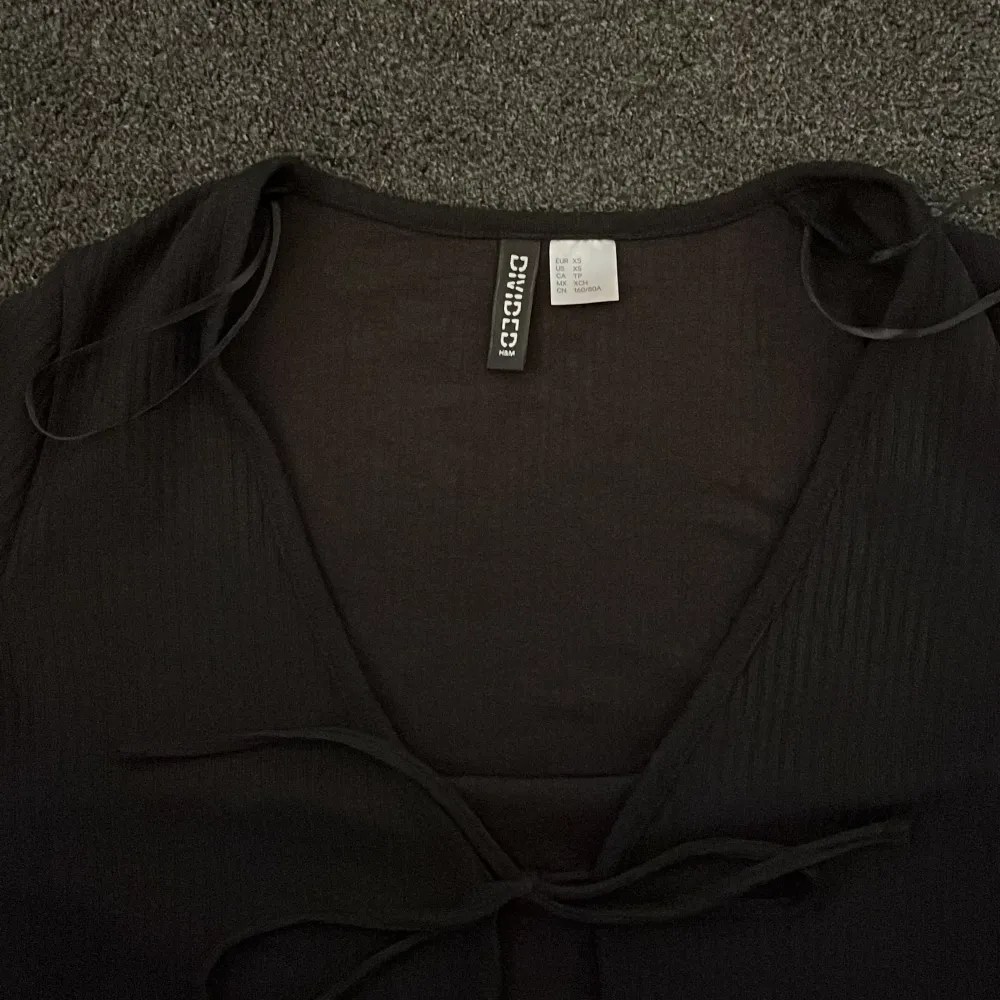 En svart söt tröja med snören i fram, du kan antingen välja att ha den knuten eller att ha den öppen så att det blir som en kofta. Den är från H&M i storlek XS. Tröjor & Koftor.