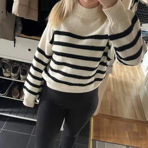 Randig stickad tröja från Stay XS - Säljer en mysig stickad tröja från Stay i storlek XS. Tröjan är vit med svarta horisontella ränder, har rund hals och ribbade muddar vid ärmslut och nederkant. Passformen är loose och ärmarna är långa, perfekt för kyliga dagar.