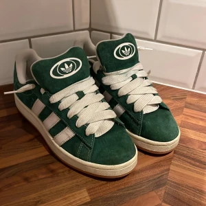 Adidas Campus gröna sneakers mocka 43 2/3 men passar för mindre storlekar med! - Snygga Adidas Campus sneakers i mörkgrön mocka med vita detaljer och breda vita snören. Klassisk retrostil med gummisula och ikonisk Adidas-logga på tungan. Perfekt för dig som gillar streetwear och vill sticka ut med färg. Skorna har rund tå och platt sula. 