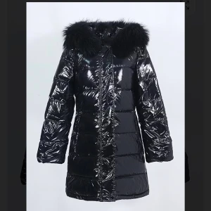 Svart glansig Garoff jacka med päls - Säljer en svart, glansig pufferjacka med fluffig svart päls runt huvan. Jackan är köpt i Garoff förs året och använd bara några gånger den är som ny.