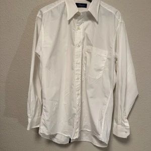 Vit skjorta från Stenströms, strl 40 - Klassisk vit skjorta från Stenströms med lång ärm, bröstficka och knappar framtill. Skjortan har en tidlös design med krage och är tillverkad i mjuk bomull. Perfekt för dig som gillar stilrena och enkla plagg.