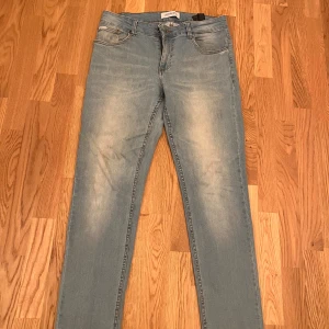 Ljusblå Slim jeans från Lindbergh - Säljer ett par ljusblå jeans från Lindbergh med klassisk femficksdesign och snygga slitningar framtill och baktill. Jeansen har raka ben och normal passform, samt en patch med Lindbergh-loggan bak i midjan. Perfekta för en Grisch stil.