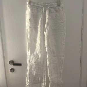 Vita linnebyxor från Chelsea Girls XS - Luftiga vita linnebyxor från Chelsea Girls i storlek XS. Byxorna har resår och snörning i midjan samt stora fickor både fram och bak. Perfekta för varma dagar när du vill ha en chill och avslappnad look.