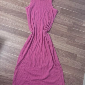 Rosa ribbad långklänning Kappahl XS - Säljer en snygg rosa långklänning från Kappahl i storlek XS. Klänningen är ärmlös och har ett ribbat tyg som ger en cool struktur. Passformen är normal och den är perfekt för dig som gillar färg och enkel stil.