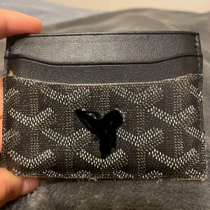 Svart plånbok med mönster - Slimmad plånbok i svart skinn med  grafiskt mönster i vitt och grått. Insidan är klargul och plånboken har flera kortfack. Perfekt för dig som vill ha något stilrent men ändå sticker ut och den är använd som ni ser på bilderna 