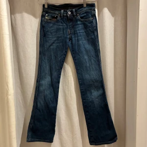 Blå bootcut jeans från Diesel - Snygga blå jeans från Diesel med klassisk bootcut passform och fem fickor. Jeansen har orange kontrastsömmar och är tillverkade i Italien. Materialet är slitstarkt. Det är ett lagat hål som ni ser på bild 4, därav priset  Imnerbenslängd: 78cm