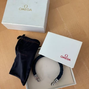 Omega Sailing bracelet - Helt sjukt eftertraktat marinblått omega armband med silvriga detaljer och röd omega logga. Allt og tillbehör som fås vid köp finns och den perfekta presenten/julklappen till dig själv eller någon annan. Supersnyggt och i toppen skick! Personligen kanske det snyggaste armbandet jag vet och nypriset ligger på 5000 kr. Tveka inte vid minsta fråga eller fundering och pris ej hugget i sten!